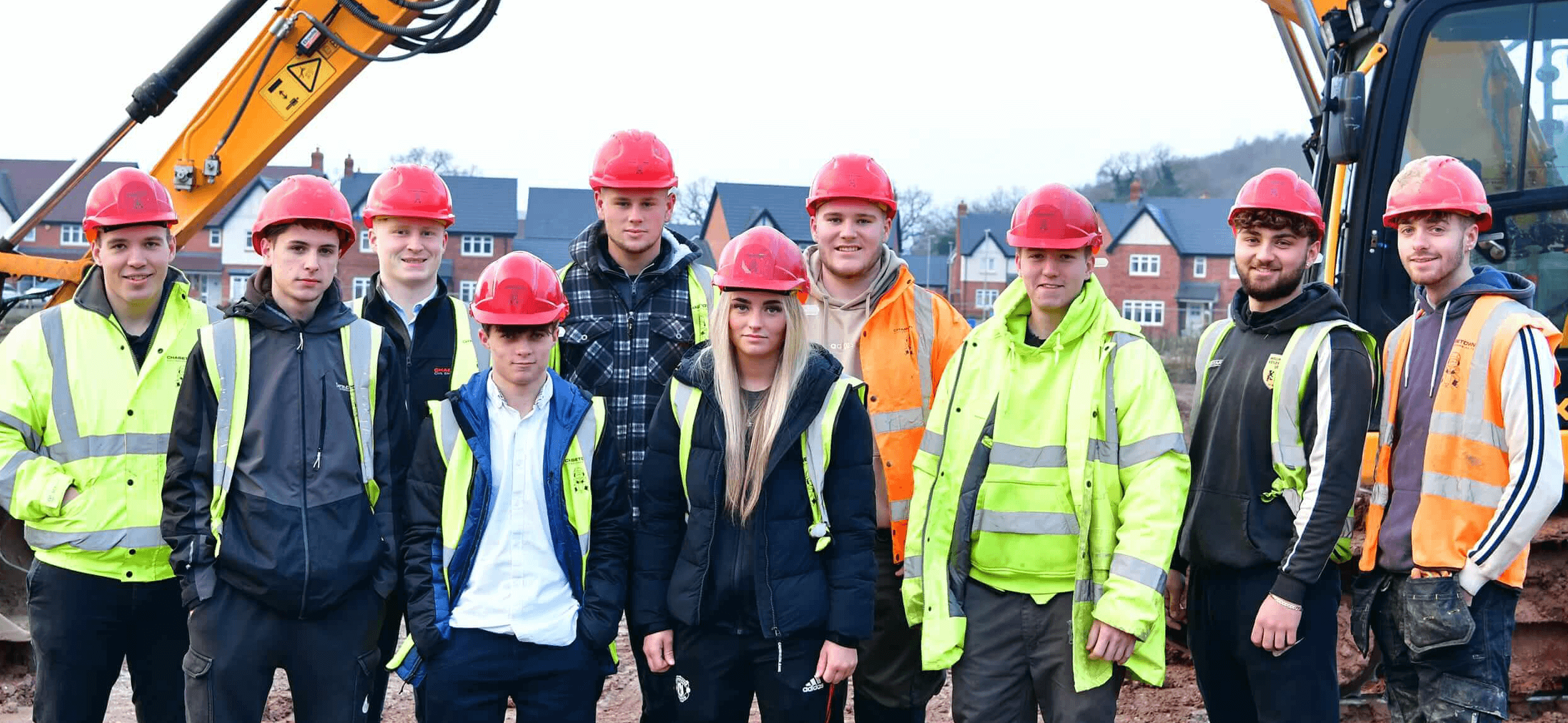Group photo of apprentices on site with hard hats in front of excavator
