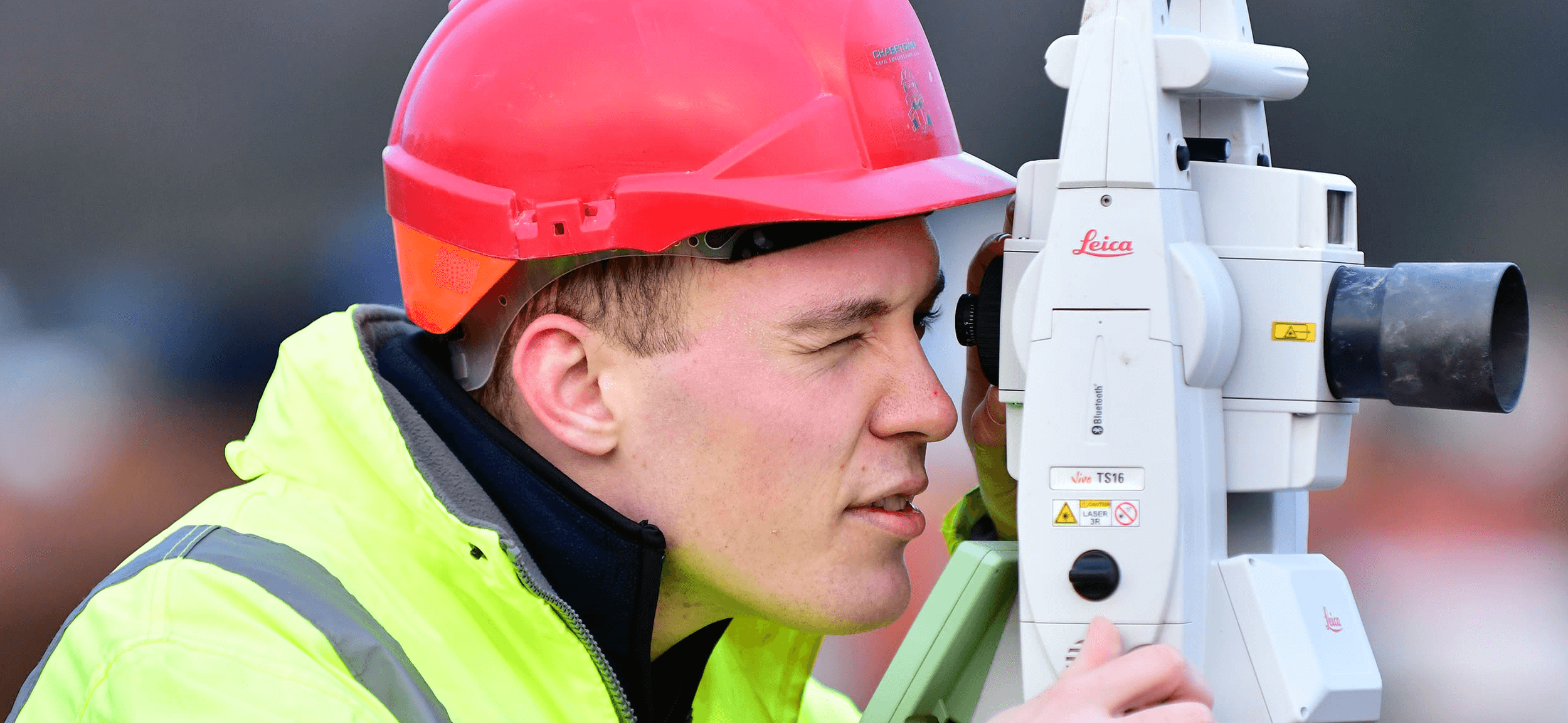 Young groundworker on site with automatic level 