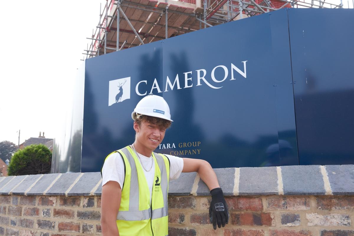 Young bricklayer on site in front of Cameron sign