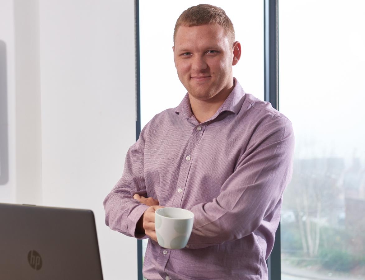 Male graduate in office in front of window 