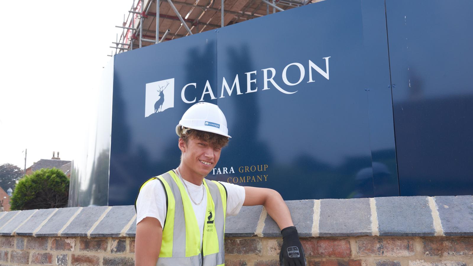 Young bricklayer on site in front of Cameron sign